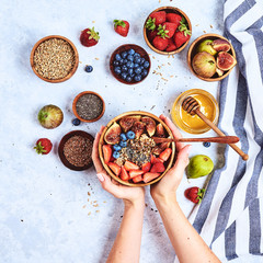 Top view showing hands eating porridge with honey, blueberries, strawberries on blue wooden table background Good morning, healthy breakfast background