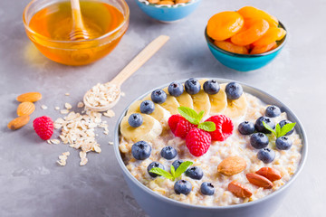 Oatmeal with berries and nuts for breakfast. Oatmeal with fruits, nuts and honey. Oatmeal with blueberries, banana and raspberries. Healthy food
