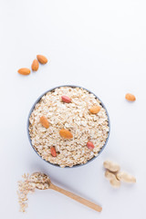 Dry oatmeal and nuts on white background. Ingredients for healthy breakfast: almonds, peanuts and oatmeal. Copy space