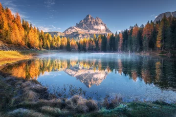 Foto auf Acrylglas Dolomiten See mit Reflexion der Berge bei Sonnenaufgang im Herbst in den Dolomiten, Italien. Landschaft mit Antorno-See, blauer Nebel über dem Wasser, Bäume mit orangefarbenen Blättern und hohen Felsen im Herbst. Farbenfroher Wald