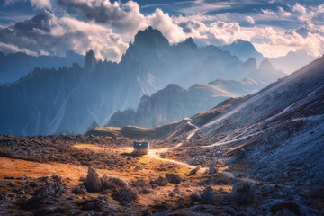 Small house in beautiful mountain valley, orange grass, stones, blue sky with clouds at sunset in autumn. Colorful landscape with building, mountains. Tre Cime park in Dolomites, Italy. Alps in fall - obrazy, fototapety, plakaty