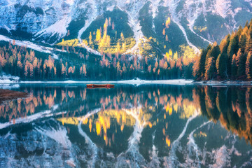 Braies lake with beautiful reflection in water at sunrise in autumn in Dolomites, Italy. Landscape with fall forest, mountains, lake, water, boats, trees with colorful foliage. Dolomiti. Italian alps - obrazy, fototapety, plakaty