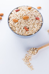 Dry oatmeal and nuts on white background. Ingredients for healthy breakfast: almonds, peanuts and oatmeal. Copy space