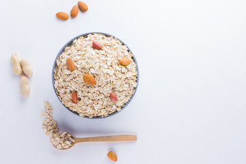 Dry oatmeal and nuts on white background. Ingredients for healthy breakfast: almonds, peanuts and oatmeal. Copy space