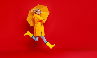 young happy emotional cheerful girl laughing and jumping with yellow umbrella   on colored red background.