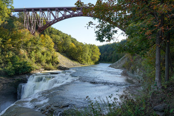Fototapeta premium Upper falls at the Letchworth State Park located in New York. Arched bridge, railroad tracks above the falls.