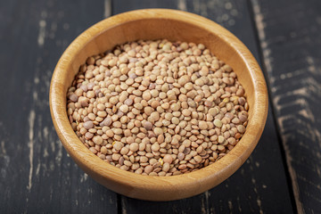 Uncooked green lentils on wooden black table