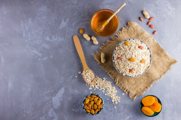 Ingredients for a healthy breakfast, nuts, oatmeal, honey, dried apricots, almonds, peanuts. Concept of natural organic food in season. Oatmeal on burlap