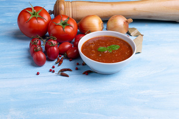 Bolognese with tomato sauce in a white plate on rustic wooden blue table background, soft light