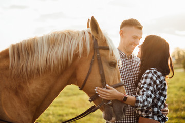 Portrait of happy loving couple spending time with horses on ranch - obrazy, fototapety, plakaty