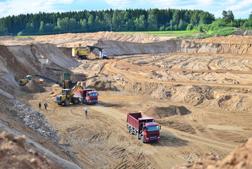 Wheel front-end loader loads sand into a dump truck. Heavy machinery in the mining quarry, excavators and trucks. Mobile jaw crusher plant with belt conveyor puts crushing and screening process