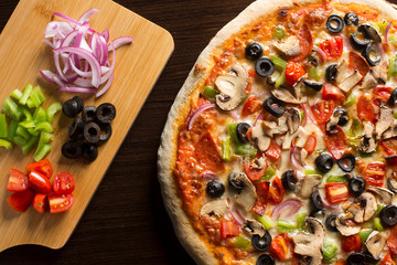 Fresh homemade pizza seen from above, on dark wooden table.