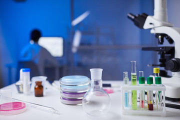 Background image of assorted laboratory equipment on workstation with test tubes and microscope in focus, copy space