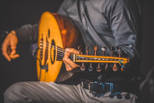 Toned image of musician playing traditional Turkish oud during concert with lights