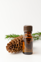 bottle of fir tree essential oil on white with pine cone
