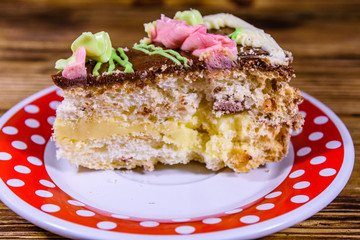 Plate with slice of Kiev cake with cream, nuts and meringue on a wooden table