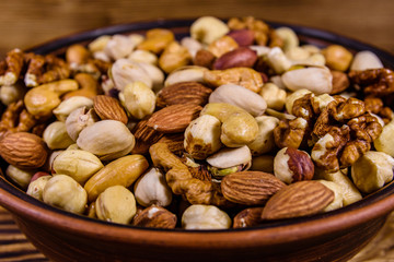 Various nuts (almond, cashew, hazelnut, pistachio, walnut) in ceramic plate on a wooden table. Vegetarian meal. Healthy eating concept