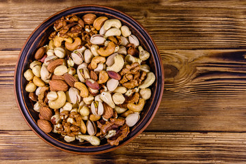 Various nuts (almond, cashew, hazelnut, pistachio, walnut) in ceramic plate on a wooden table. Vegetarian meal. Healthy eating concept. Top view