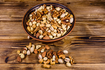 Various nuts (almond, cashew, hazelnut, pistachio, walnut) in ceramic plate on a wooden table. Vegetarian meal. Healthy eating concept