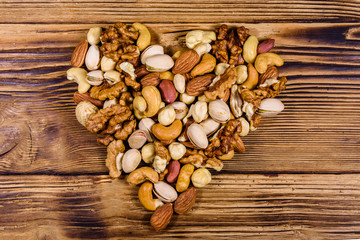 Various nuts (almond, cashew, hazelnut, pistachio, walnut) in shape of heart on a wooden table. Vegetarian meal. Healthy eating concept