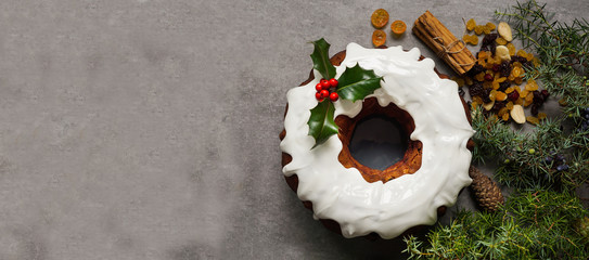 Christmas cake, decorated with christmas holly,  fruitcake on the grey stone background