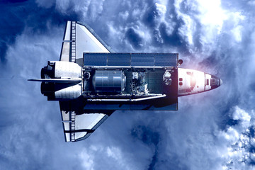 Space shuttle above the earth in the clouds. Elements of this image were furnished by NASA.