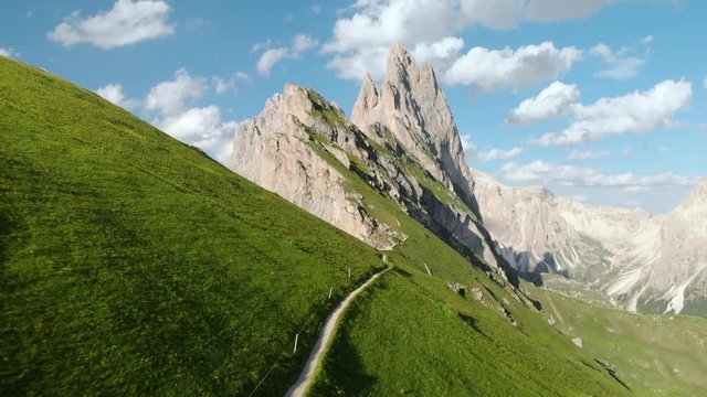 Mountain peaks in the Alps with blooming pastures and hiking trail in summer