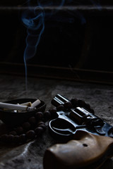 Revolver and rosary. Revolver and rosary with an ashtray.
