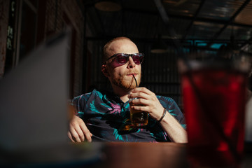 Man in sunglasses drinks lemonade and awaits his lunch