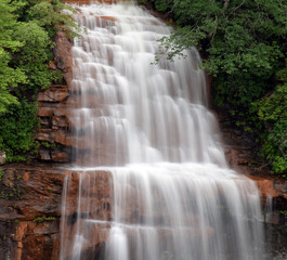 A waterfall cascades over red rock.