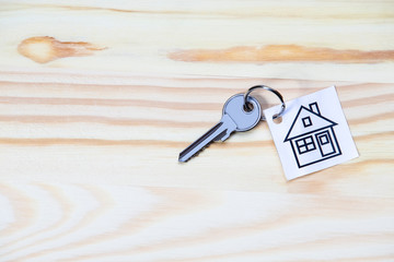 Home Concepts. Home or House Symbol Along With Silver Key Against Vintage Wooden Background.
