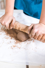 Pottering Ideas and Concepts. Closeup of Hands of Female Worker Rolling a Piece of Wet Clay on Table Before Moulding.