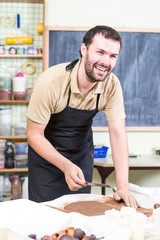 Happy and Smiling Male Potter Preparing a Piece of Wet Clay Using Ruler on The Table in Workshop.