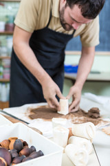 Professional Male Potter Pressing a Piece of Wet Flat Clay With Mould on The Table in Workshop.