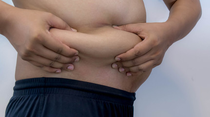 Overweight Asian obese men, He is feeling ill and worried about his excess weight. He squeezed his belly, showing the excess fat that was isolated on a white background