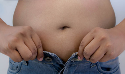 Overweight Asian obese men, He is feeling ill and worried about his excess weight. He squeezed his belly, showing the excess fat that was isolated on a white background