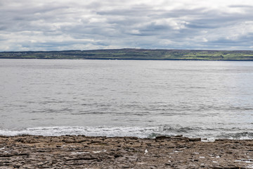 Rocks and beach with Doolin farms and Cliffs of Moher in background in Inisheer island