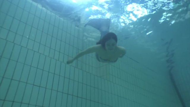 Underwater model mermaid costume in swimming pool. Young woman freediver swims in undine water nymph costume with monofiin.