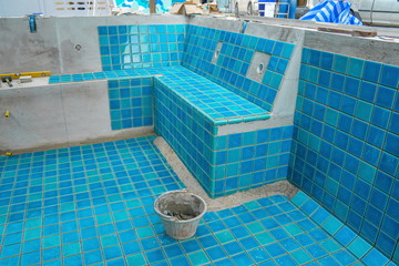 Tiled pool. The man hand while using spacer for installing tiles. construction work.Construction...