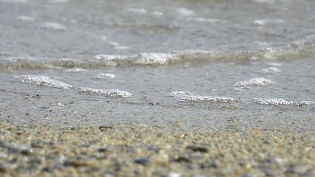 ow point of view over an out-of-focus pebbled beach with a splashing wave