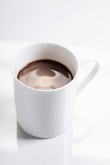 White ceramic cup of hot cocoa on top of white marble background