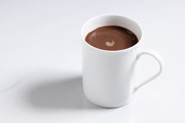 White ceramic cup of hot cocoa on top of white marble background