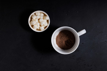 White ceramic cups of hot cocoa with marshmallows on top of rustic black background
