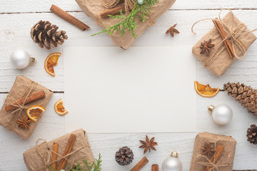 Christmas frame. Postcard with Christmas tree branch and gifts, on white wooden background.