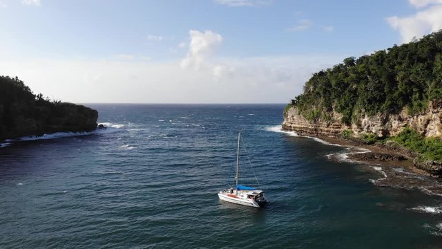 Catamaran yacht anchored in a sheltered bay on an island to avoid the storm