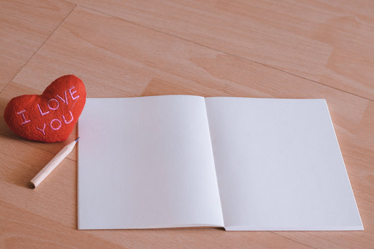Red heart "I LOVE YOU" with plain notebook and pencil on wood floor. Minimal and clean style with copy space. Photo concept of couple, family, friend, lover and soul mate. Love is all around.
