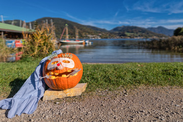 A doctor helloween pumpkin outside in front of an idyllic lake.