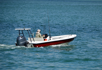 Red and white fishing skiff powered by a single outboard engine