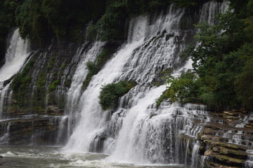 Fototapeta na wymiar Multiple waterfalls over rock.