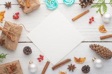 Christmas frame. Postcard with Christmas tree branch and gifts, on white wooden background.